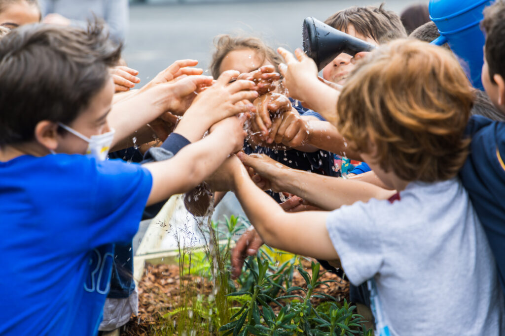 Crianças a brincar com água no espaço do projeto PLANTEIA
