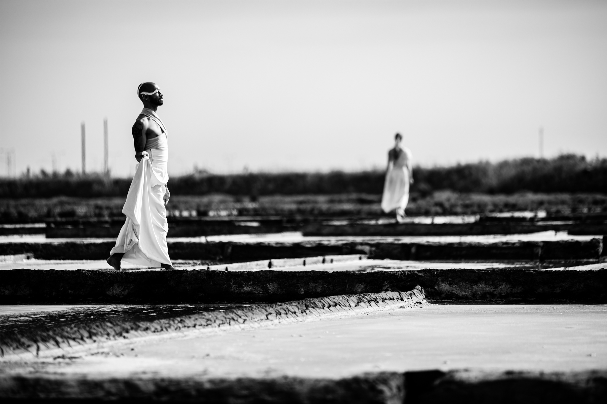 Performers caminham em paisagem aberta durante performance