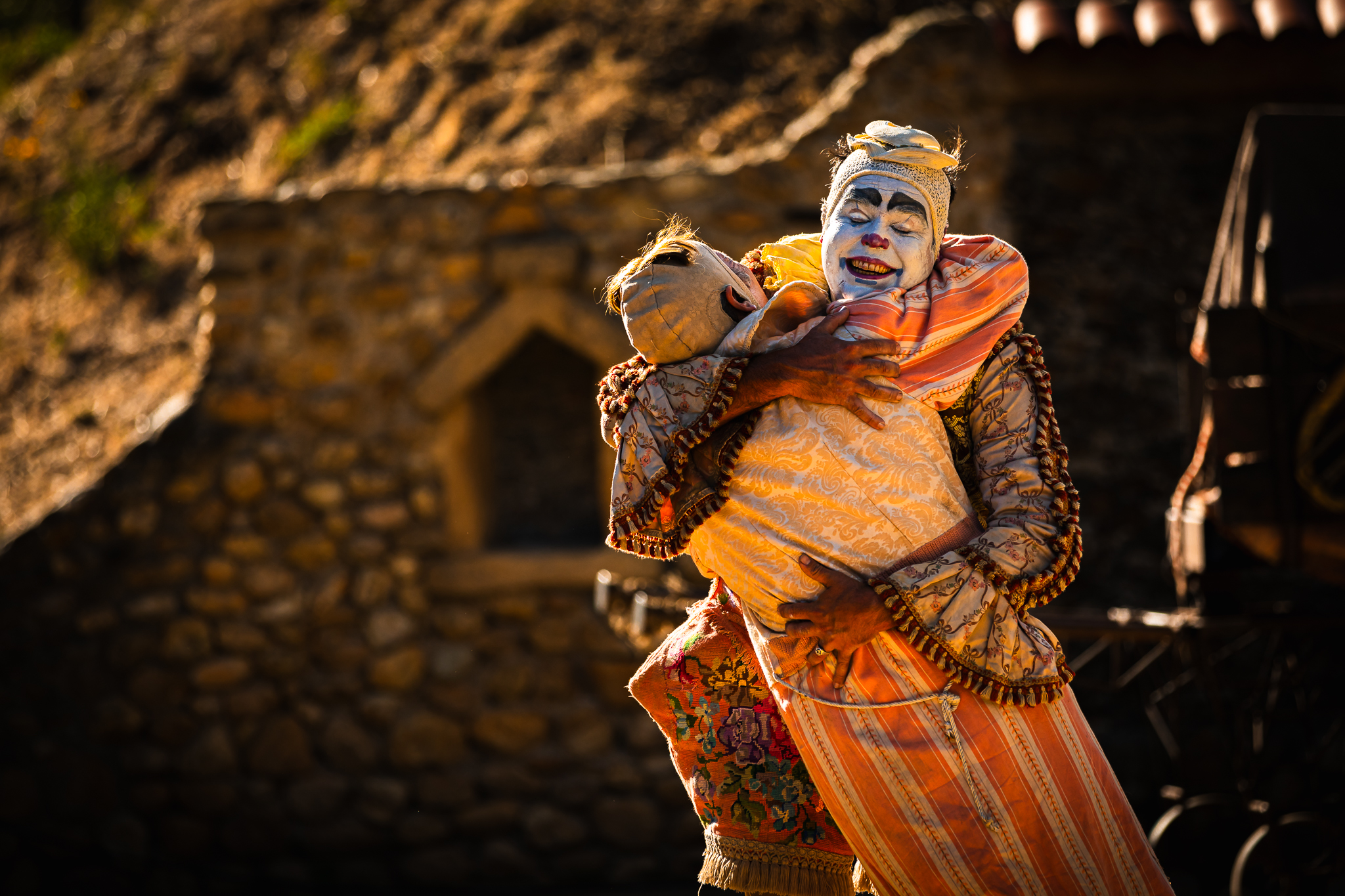 Performer com figurino teatral segura boneco em performance narrativa