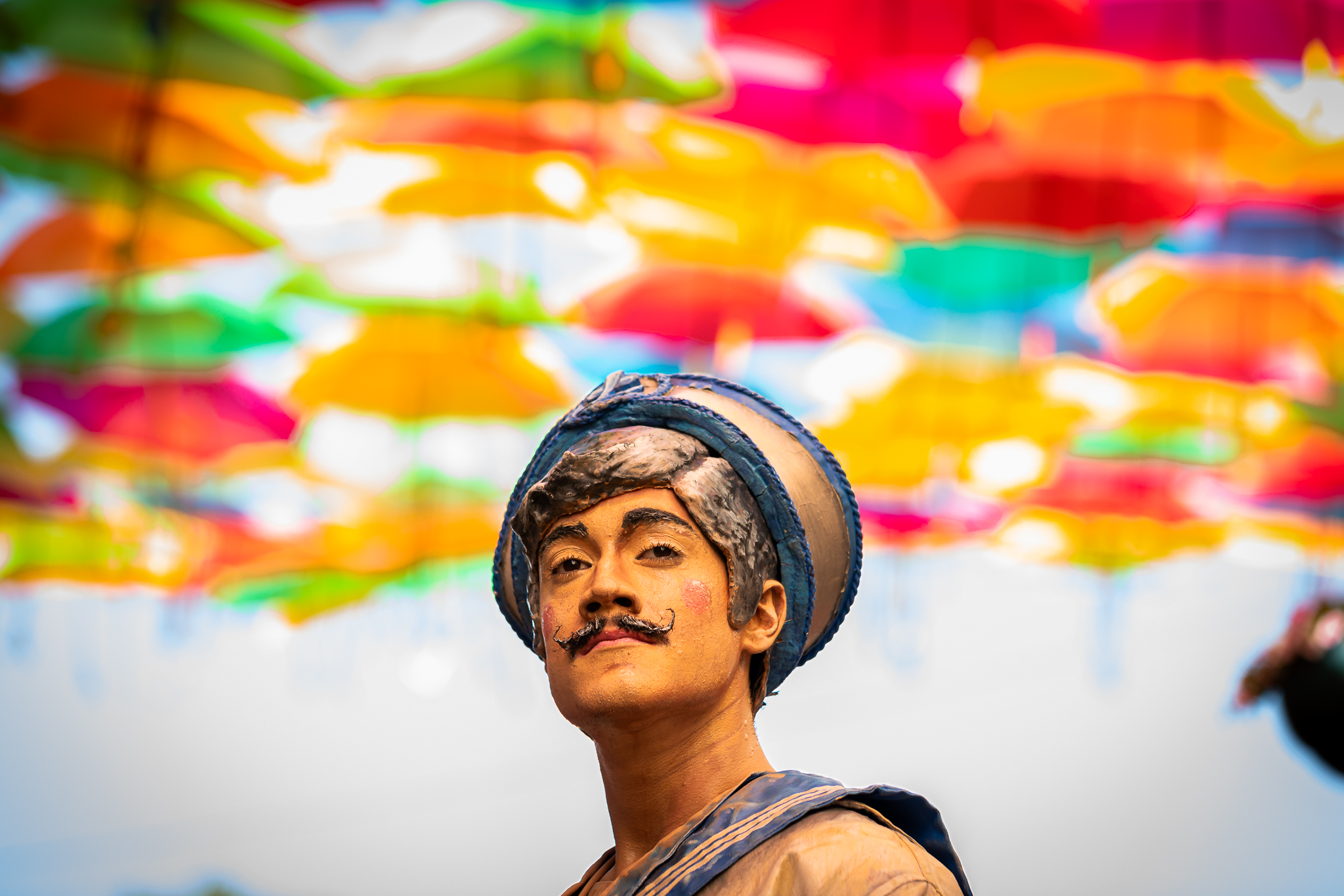 Retrato de performer em espaço urbano com instalação de guarda-chuvas