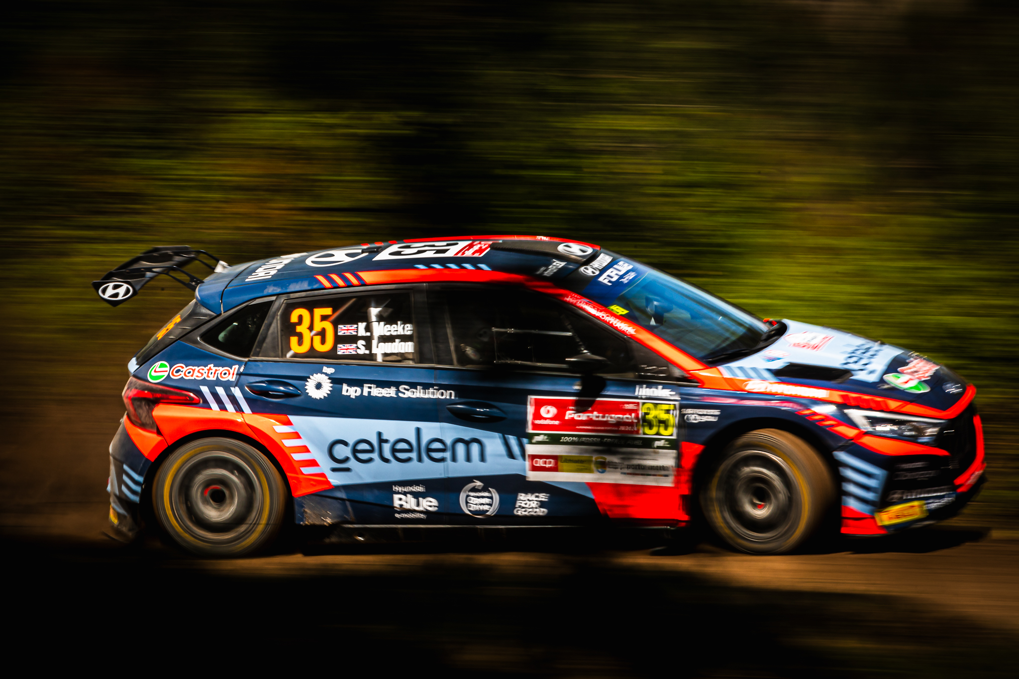 Carro de rally em movimento lateral com marcas de patrocinadores