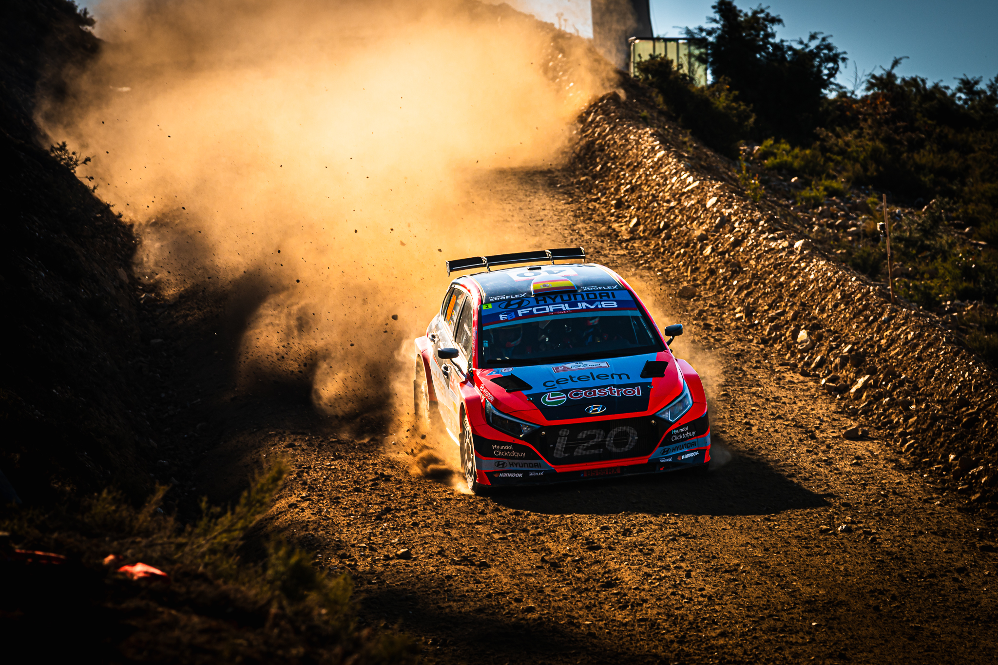 Carro de rally atravessa estrada de terra envolto em poeira